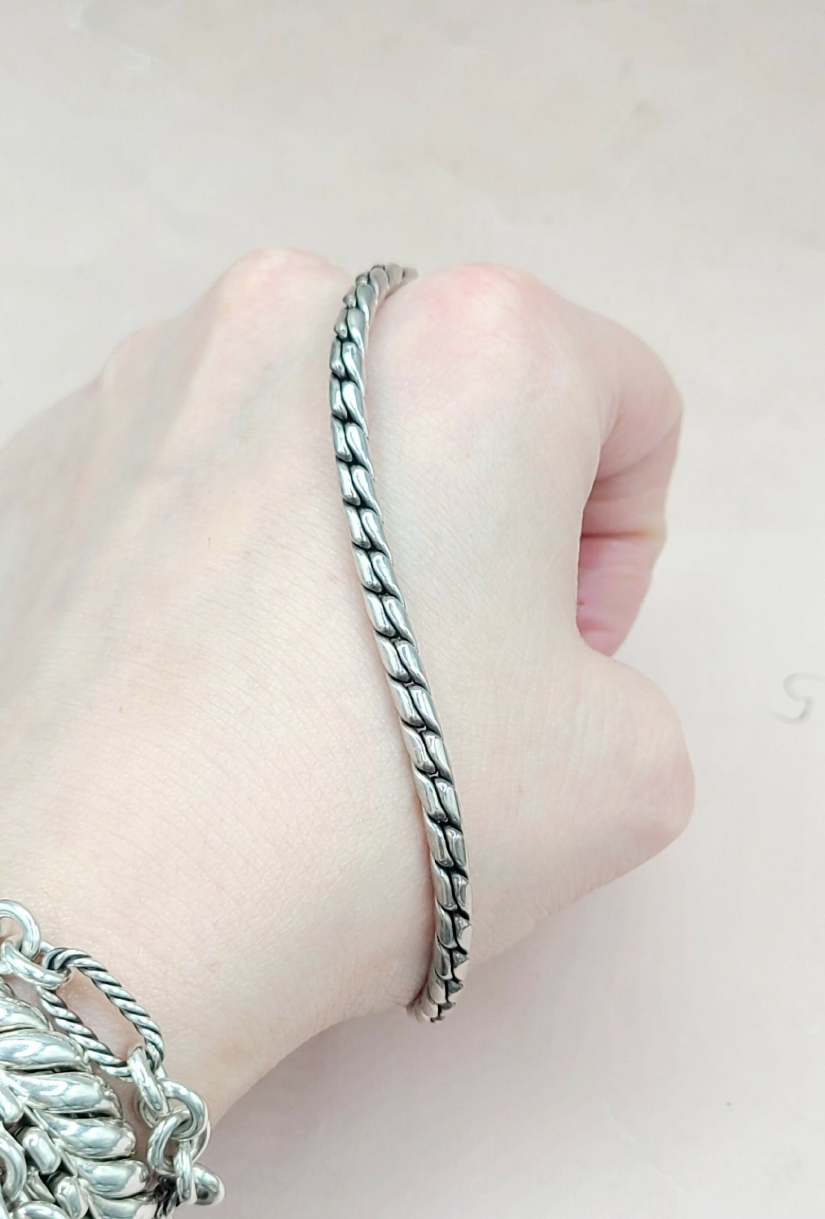 Silver bracelet on a person's wrist against a light background