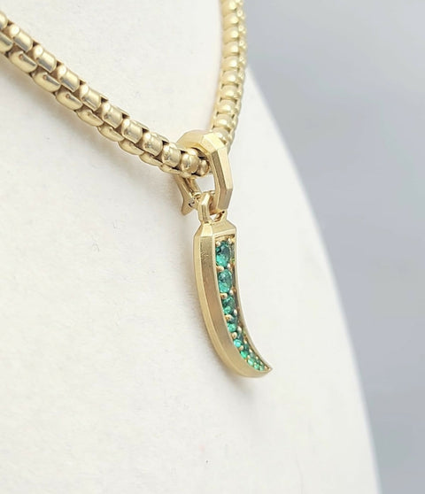 A gold-tone chain necklace with a curved crescent moon pendant featuring a row of small green stones, displayed on a white jewelry bust.