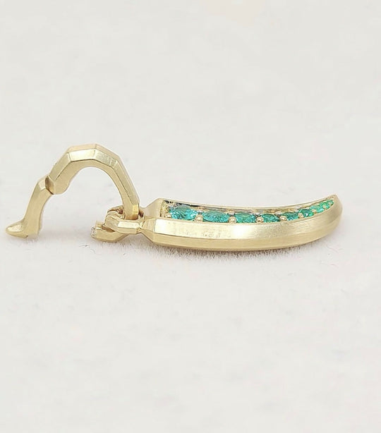 A gold-toned curved earring with a row of small green stones set along the front, photographed on a plain light background.