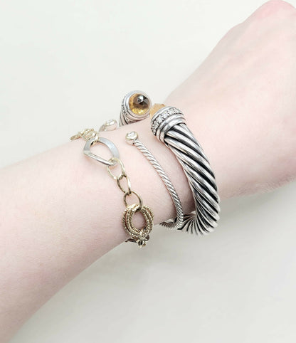 Close-up of a wrist wearing multiple silver bracelets on a light background