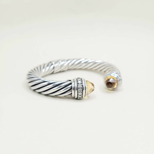 Silver cable-style bracelet with a gold accent on a white background