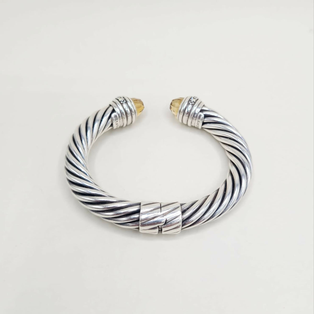 Silver and gold braided bracelet on a light gray background