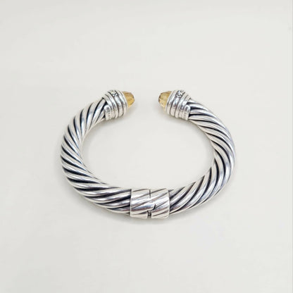 Silver and gold braided bracelet on a light gray background