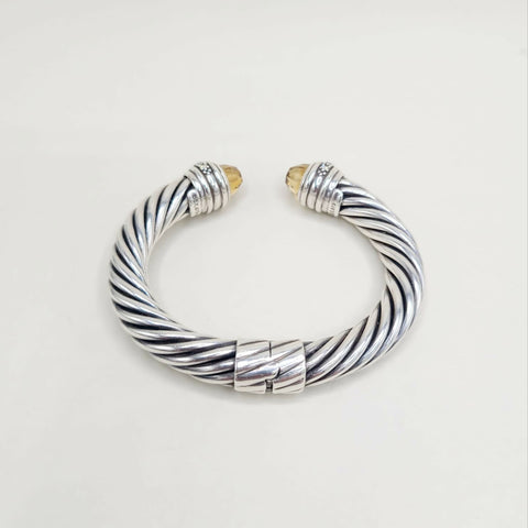 Silver and gold braided bracelet on a light gray background