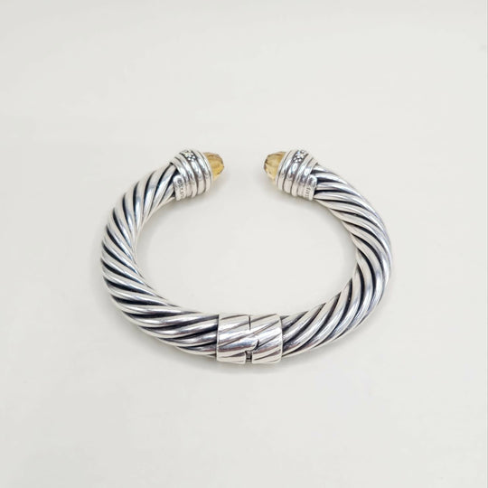 Silver and gold braided bracelet on a light gray background