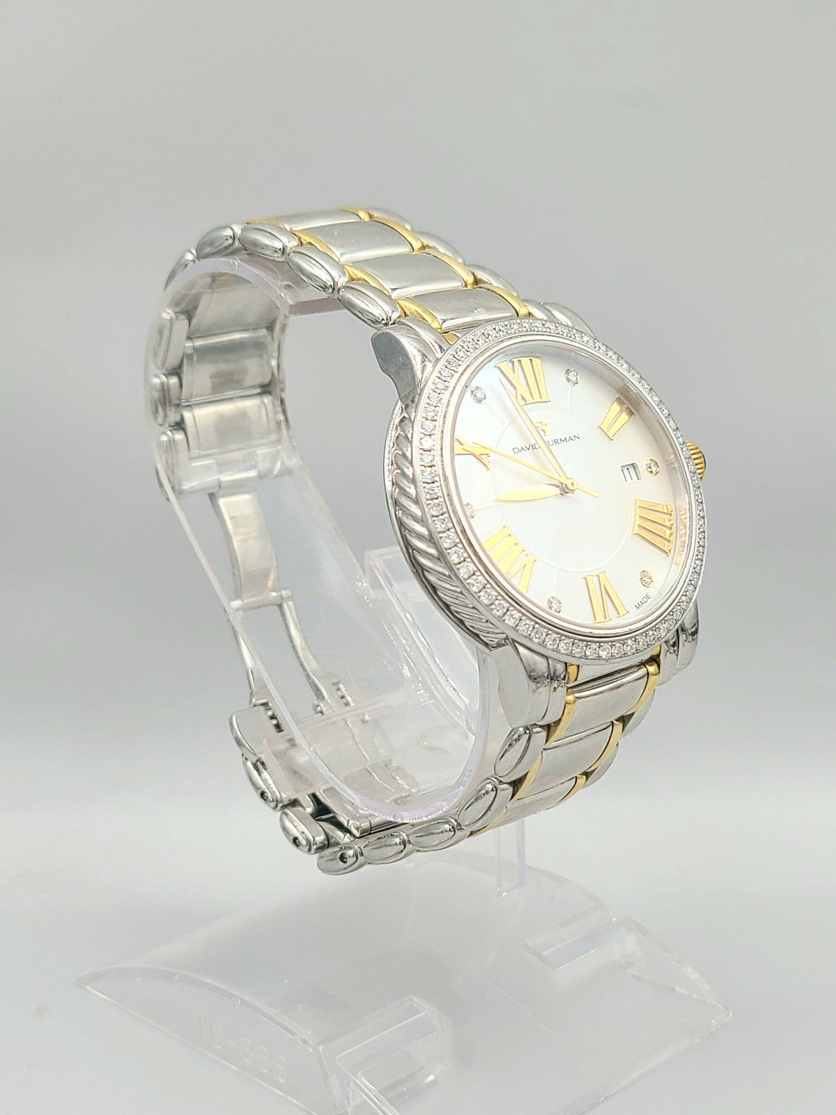 Two-tone watch with silver and gold band on a clear stand against a light gray background
