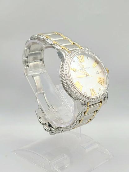 Two-tone watch with silver and gold band on a clear stand against a light gray background