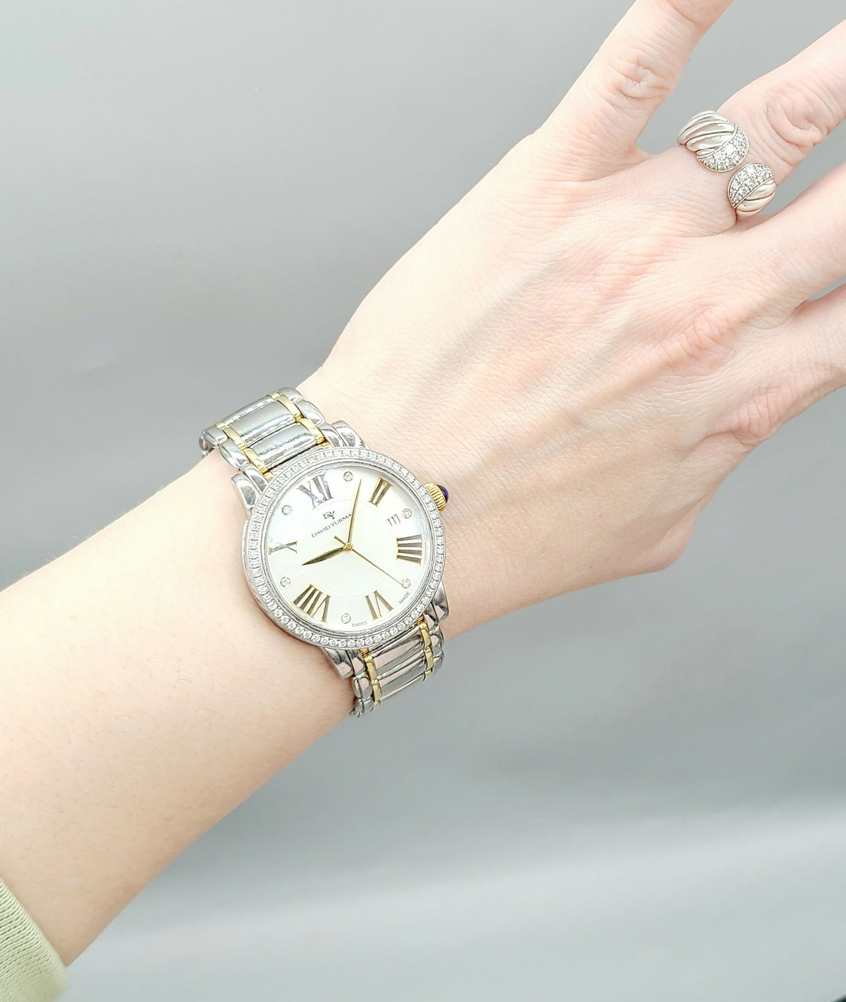 Hand wearing a silver watch with a gray background