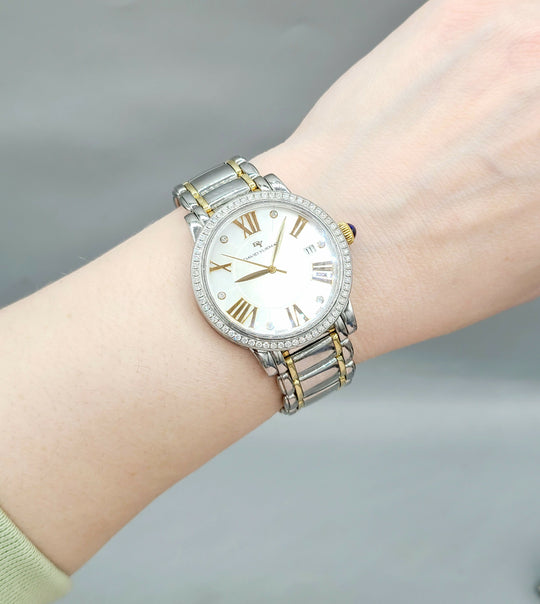 Silver and gold watch on a wrist with a gray background