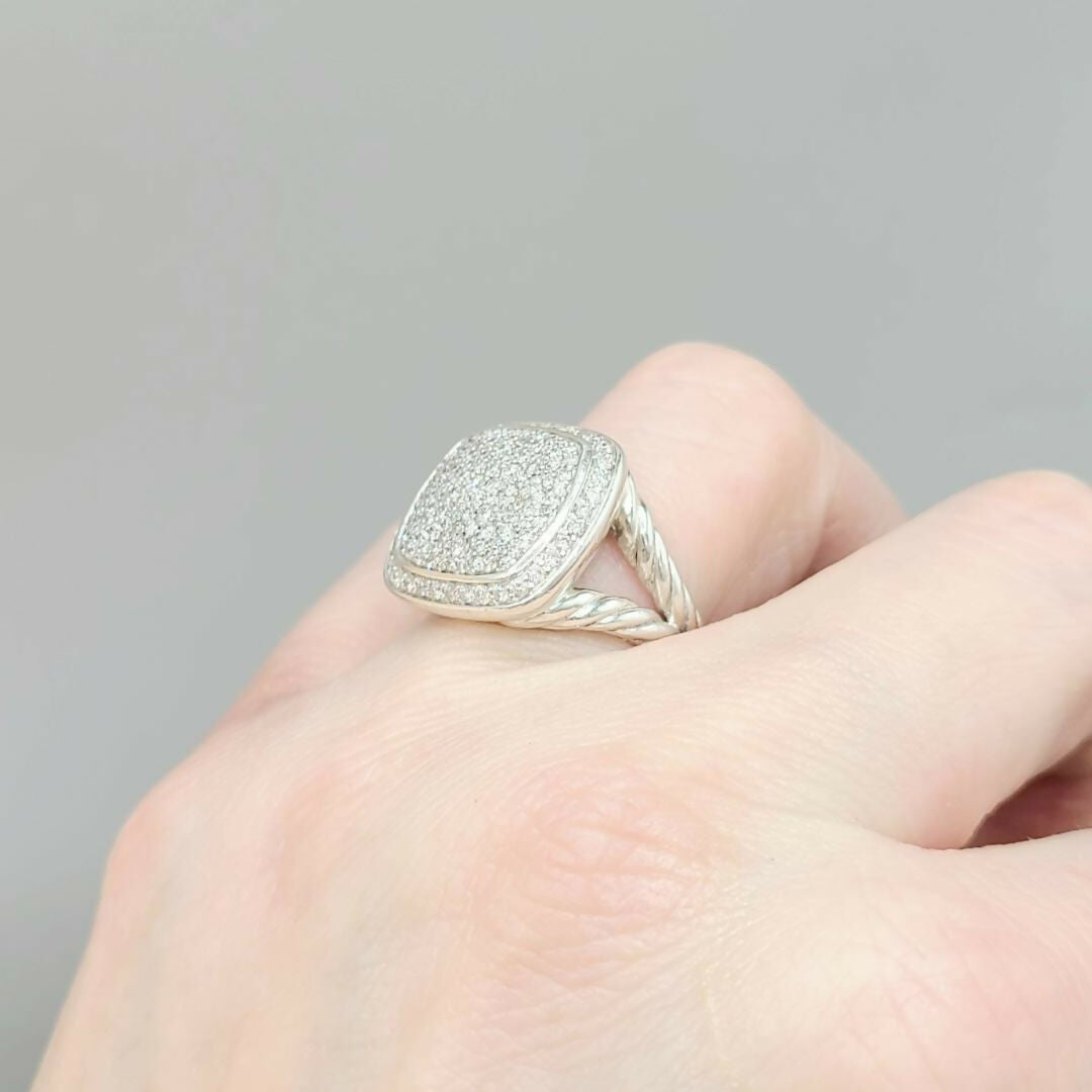Silver ring with a textured surface on a finger against a gray background
