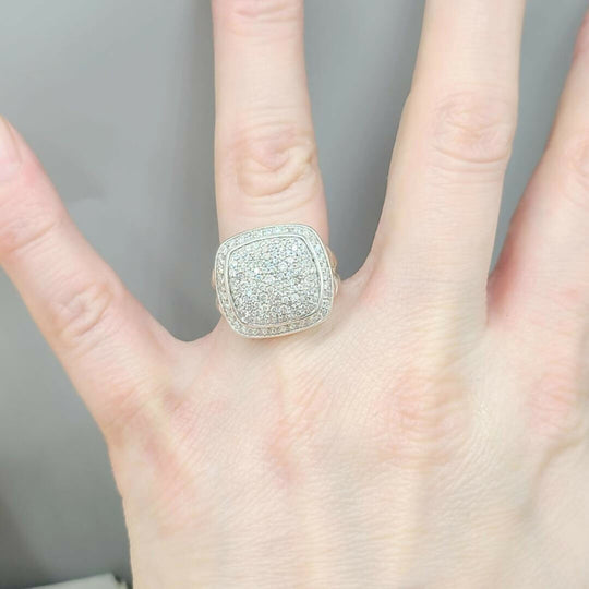 Silver ring with gemstones on a hand against a neutral background