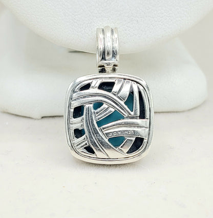 Silver pendant with blue and black design on a white background