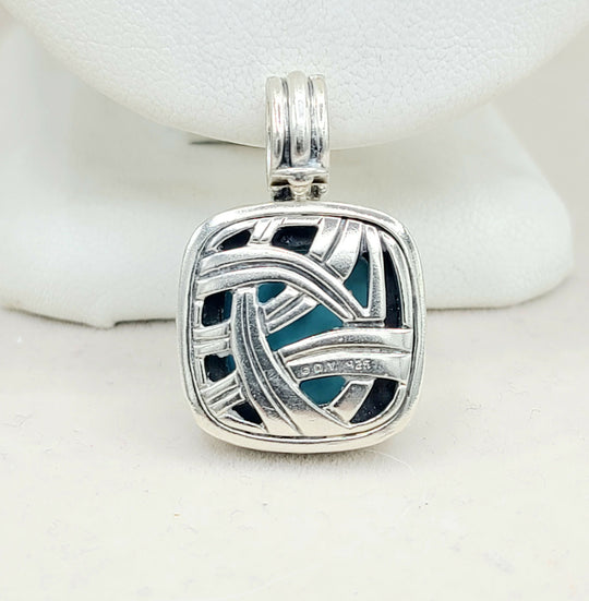 Silver pendant with blue and black design on a white background