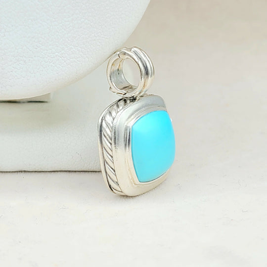 Silver pendant with a blue stone on a white background