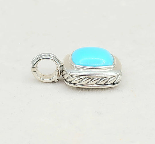 Silver pendant with a turquoise stone on a light gray background