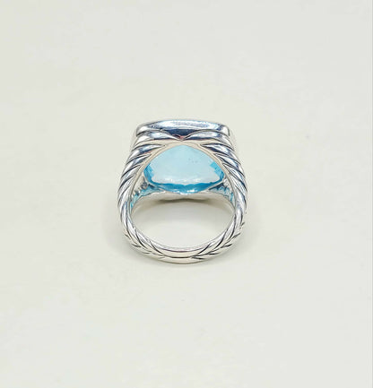 Silver ring with a blue gemstone on a light gray background