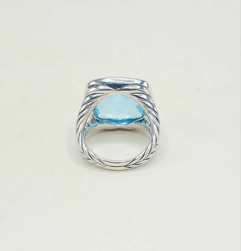 Silver ring with a blue gemstone on a light gray background