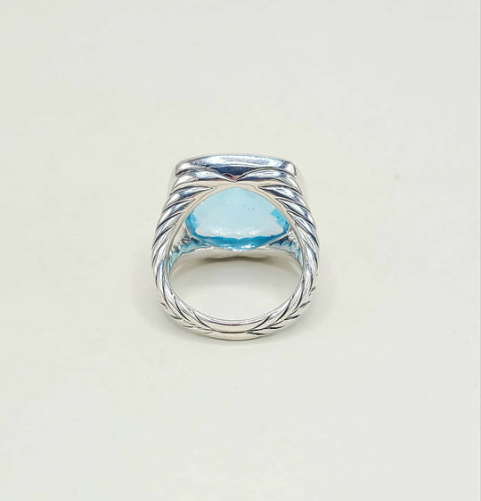 Silver ring with a blue gemstone on a light gray background