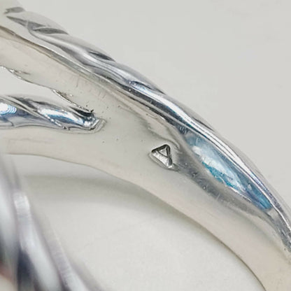 Close-up of a silver ring with a visible brand logo on a light gray background