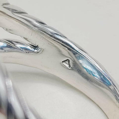 Close-up of a silver ring with a visible brand logo on a light gray background
