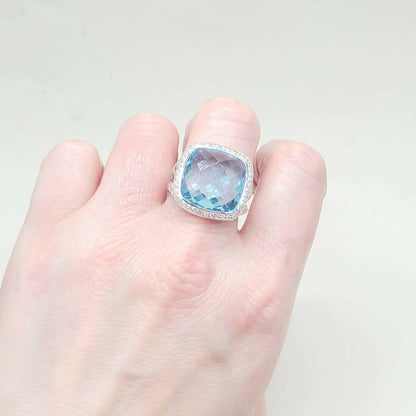 Ring with a blue gemstone on a hand against a light background