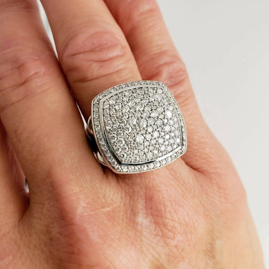 Silver ring with gemstones on a hand against a white background
