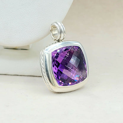 Silver pendant with a purple gemstone on a white background