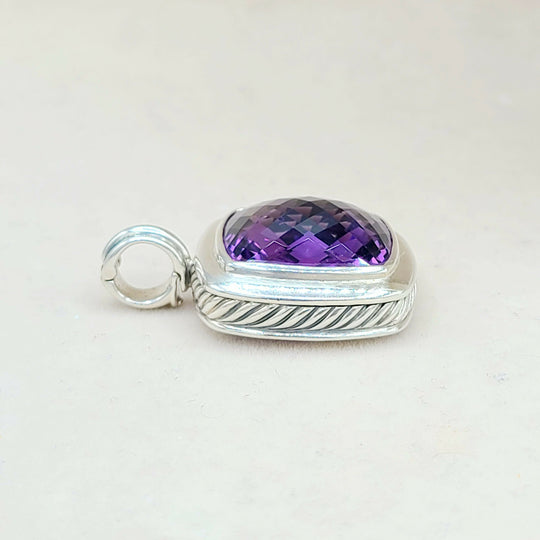 Silver pendant with a purple gemstone on a light gray background