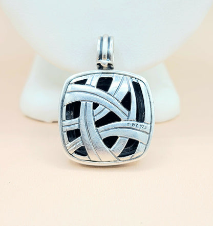 Silver pendant with intricate design on a light background