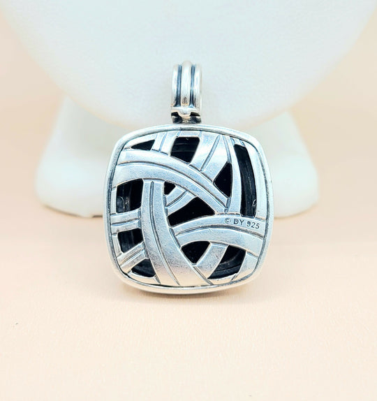 Silver pendant with intricate design on a light background