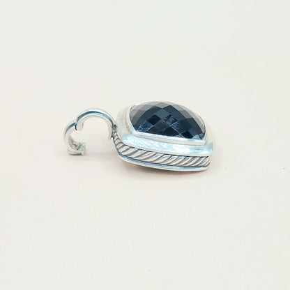 Silver pendant with blue gemstone on a white background