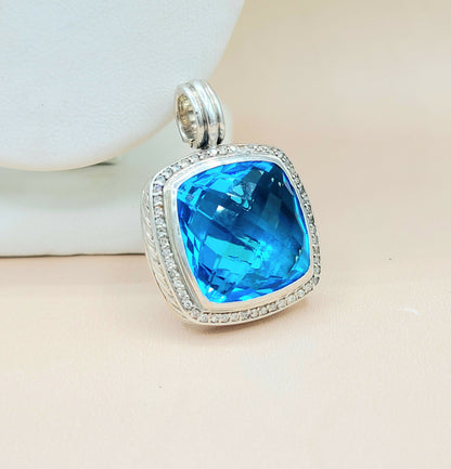 Silver pendant with a blue gemstone on a beige surface