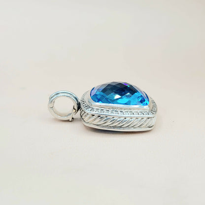 Silver pendant with a blue gemstone on a light gray background