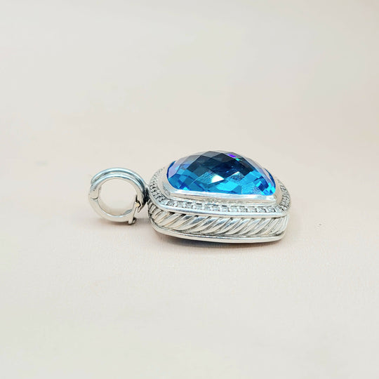 Silver pendant with a blue gemstone on a light gray background