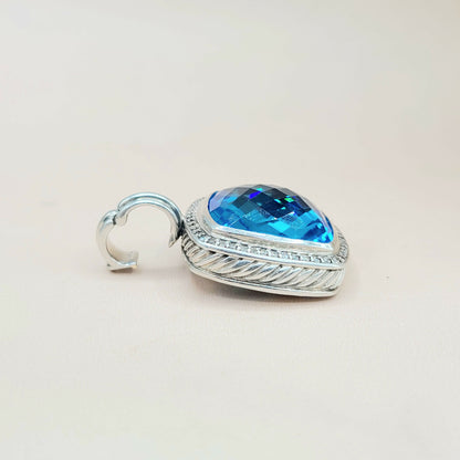 Silver pendant with a blue gemstone on a light beige background