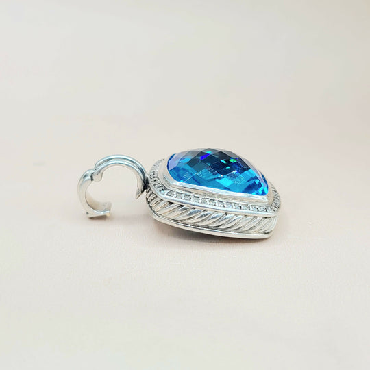 Silver pendant with a blue gemstone on a light beige background