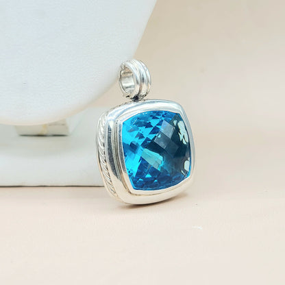 Silver pendant with a blue gemstone on a light background