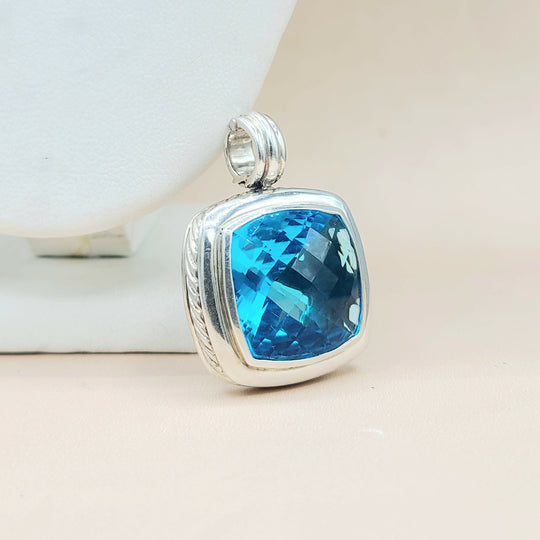 Silver pendant with a blue gemstone on a light background
