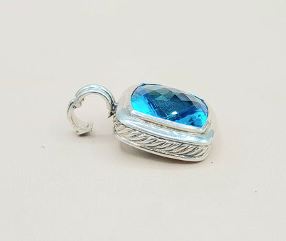 Silver pendant with a blue gemstone on a light gray background