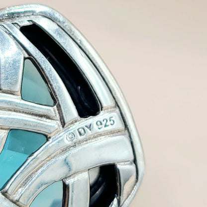 Close-up of a silver earring with '925' stamp on a beige background