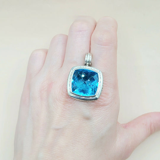 Blue gemstone ring on a hand against a beige background