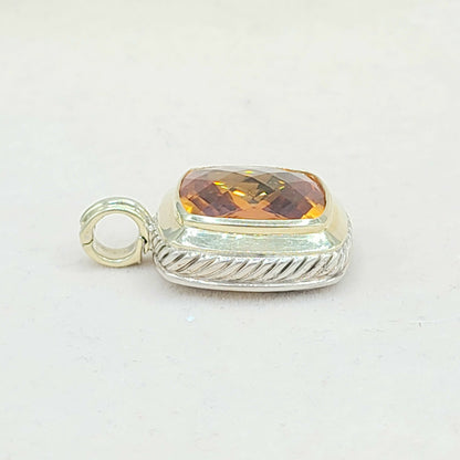 Silver pendant with a yellow gemstone on a white background