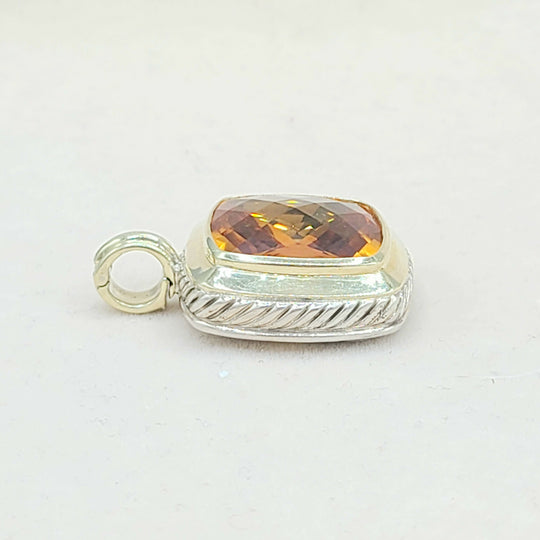 Silver pendant with a yellow gemstone on a white background
