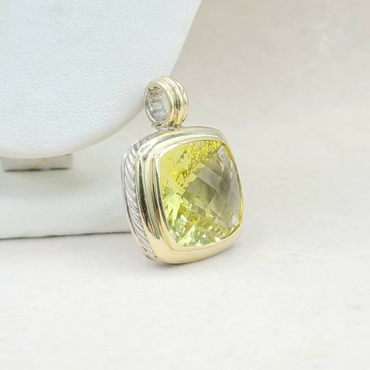 Gold pendant with a yellow gemstone on a light background