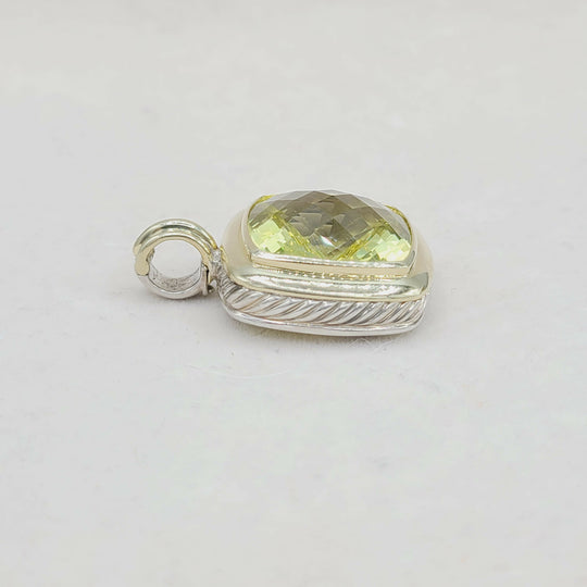 Silver pendant with a yellow gemstone on a light gray background