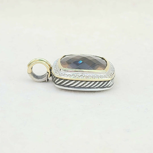 Silver and gold pendant with a gemstone on a white background