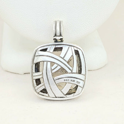 Silver pendant with intricate design on a white background