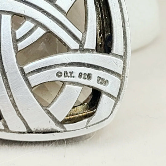 Close-up of a silver pendant with engraved text on a light background