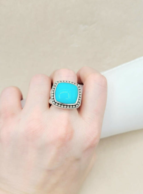Turquoise ring on a finger with a neutral background