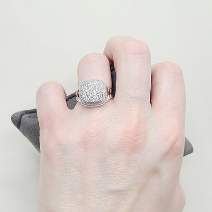 Hand wearing a silver ring with a textured band on a neutral background